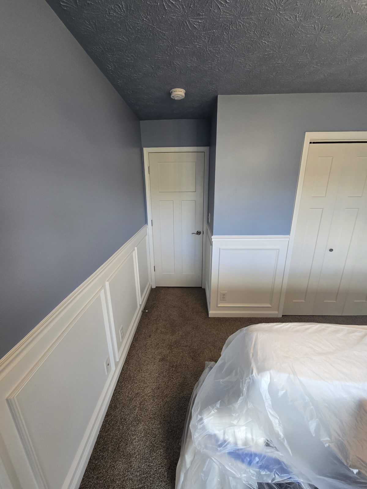 White picture frame panels and chair rail below blue gray walls in a Lafayette bedroom