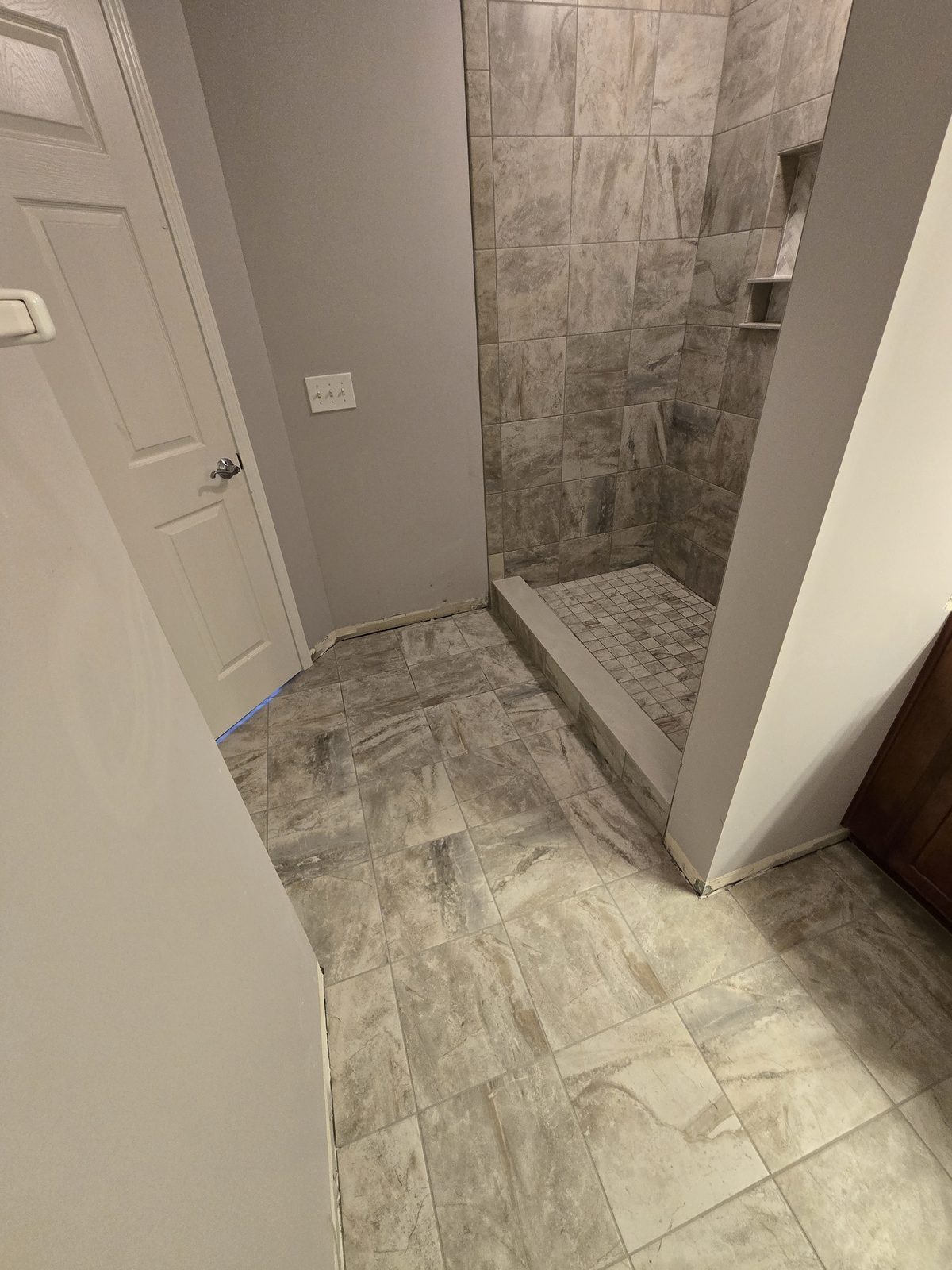 Large format floor tile running toward the new tile shower in a Lafayette bathroom