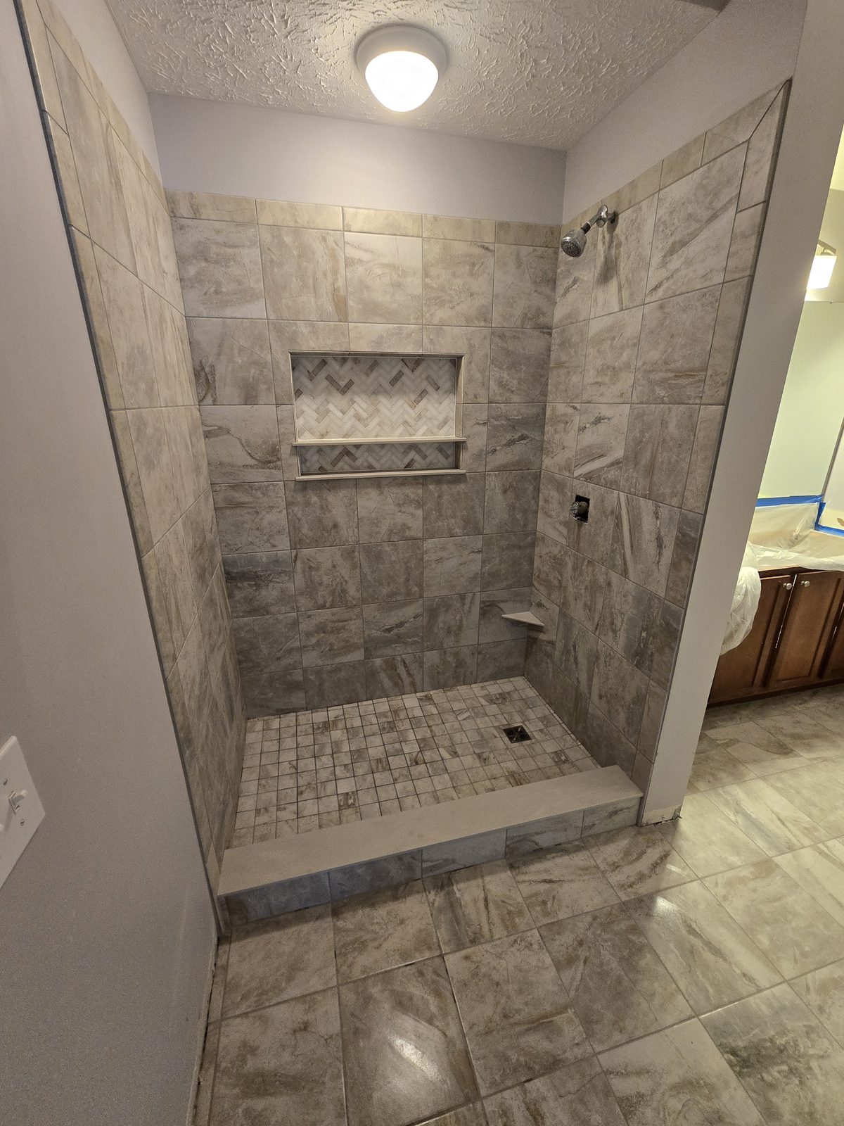 Mosaic tile shower floor and herringbone lined niche in a Lafayette bathroom
